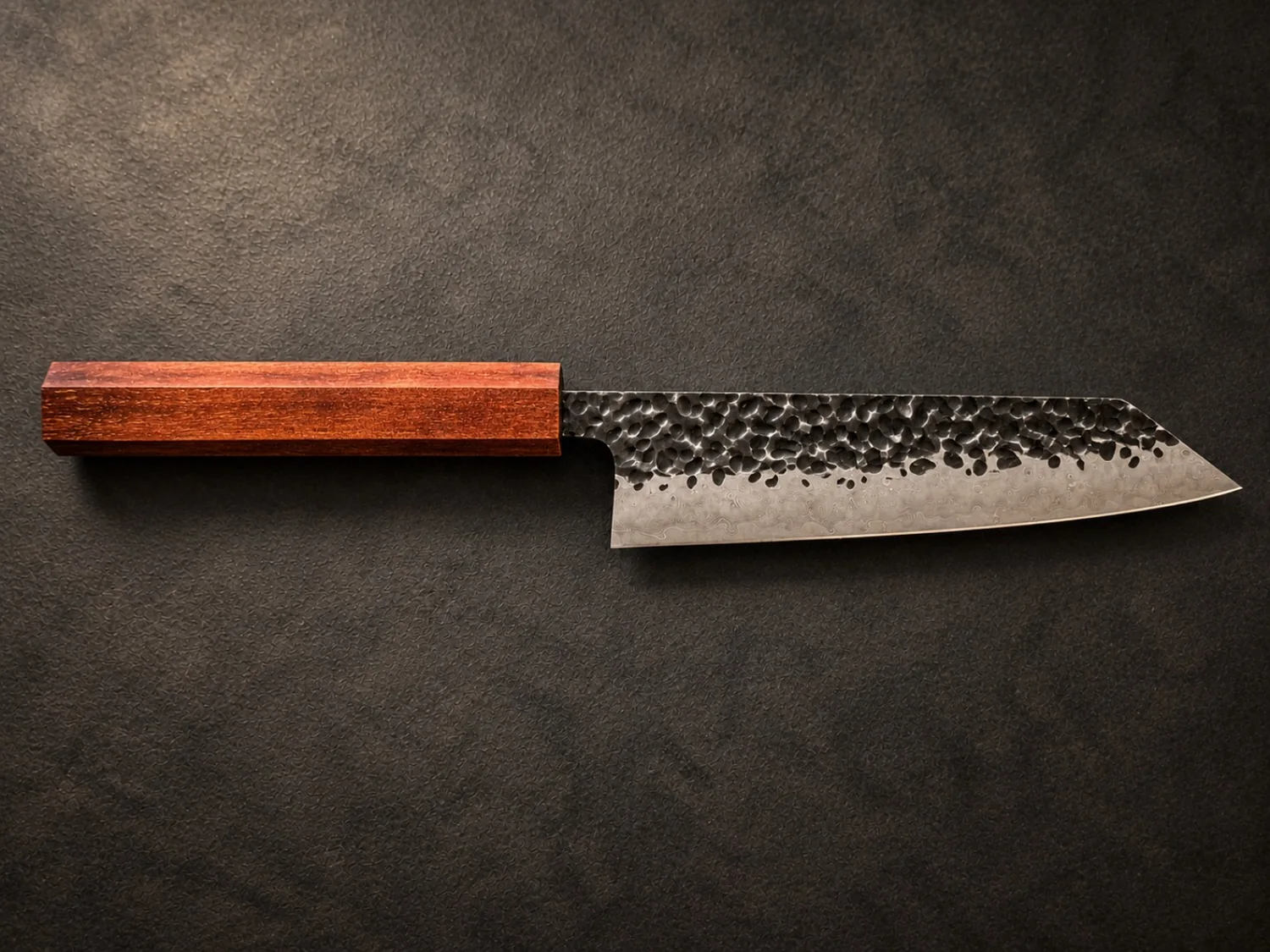 A completed Japanese-profile knife with a deep warm reddish-brown timber handle.